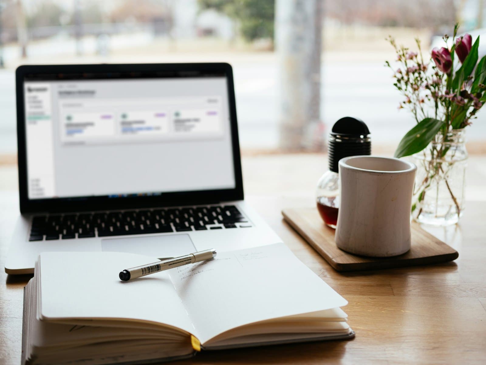 Laptop mit geöffneter Magister Unterweisungsplattform auf einem Schreibtisch mit Notizbuch und Kaffee